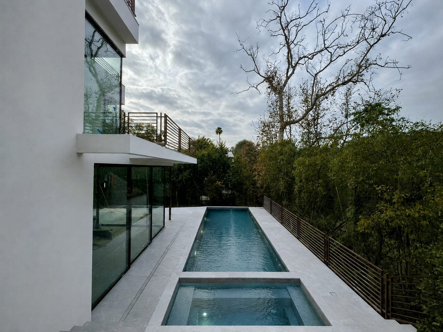 Modern glass residence with a lap pool at dusk, Westside Los Angeles — HR Development Inc.